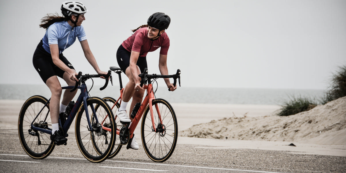 To piger på cykel med strand i baggrunden